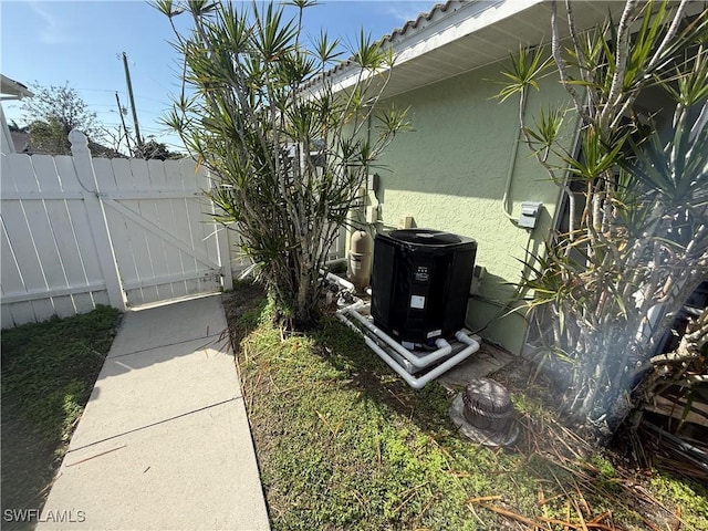 details featuring central air condition unit, a gate, fence, and stucco siding