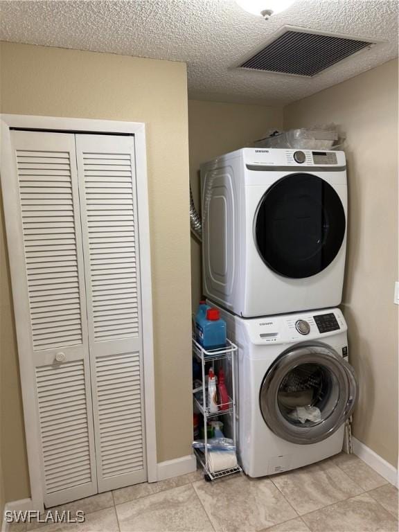 washroom with laundry area, visible vents, stacked washer / drying machine, a textured ceiling, and light tile patterned flooring