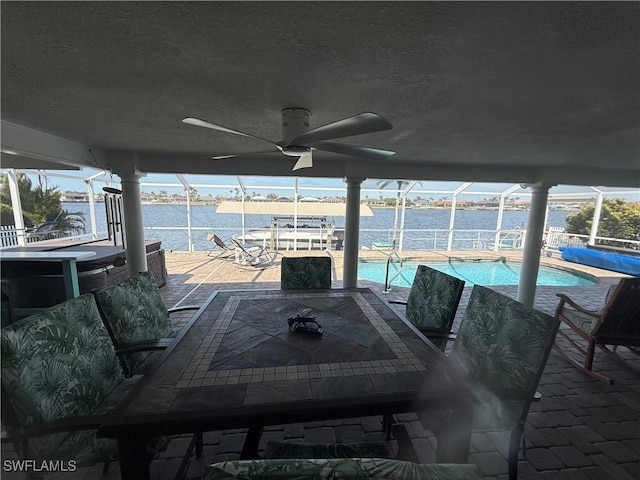 view of patio / terrace with a lanai, a water view, an outdoor pool, and ceiling fan