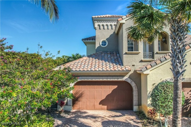 mediterranean / spanish-style home with a garage, a tile roof, driveway, and stucco siding