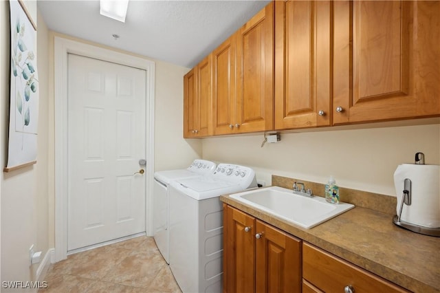 clothes washing area with cabinet space, light tile patterned floors, separate washer and dryer, and a sink