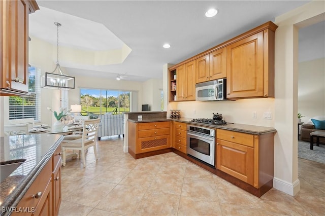 kitchen with recessed lighting, appliances with stainless steel finishes, dark stone countertops, a chandelier, and a peninsula