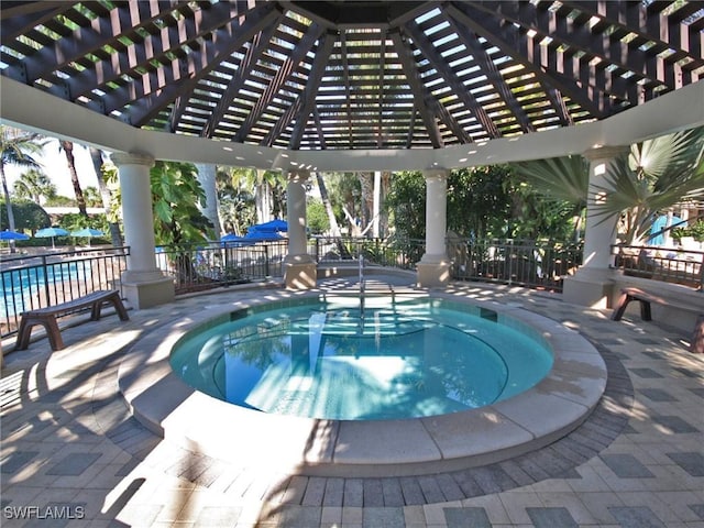 view of pool with a hot tub, fence, a pool, and a pergola