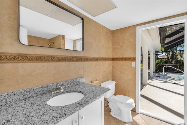 bathroom featuring vanity, tile walls, tile patterned floors, and toilet