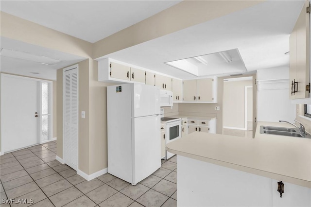 kitchen featuring light tile patterned flooring, white cabinetry, sink, kitchen peninsula, and white appliances