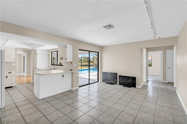 kitchen featuring light tile patterned flooring, sink, white cabinets, and kitchen peninsula