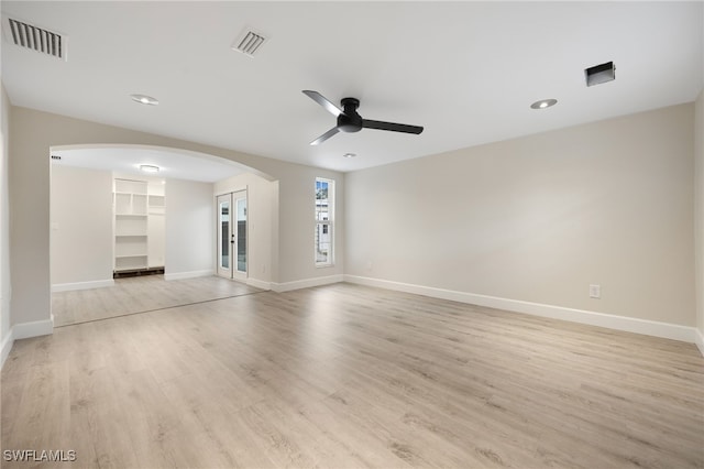 spare room with light wood finished floors, visible vents, arched walkways, and baseboards