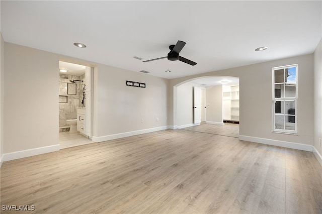 spare room featuring baseboards, arched walkways, ceiling fan, light wood-type flooring, and recessed lighting