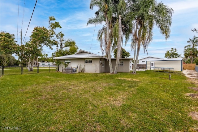 rear view of house with a fenced backyard, a lawn, and stucco siding