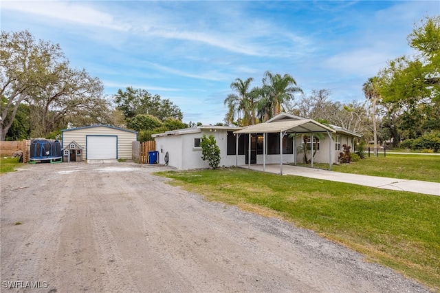ranch-style house with a detached garage, an outdoor structure, a sunroom, dirt driveway, and a front yard
