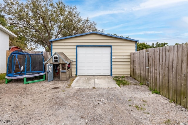 detached garage featuring a trampoline and fence