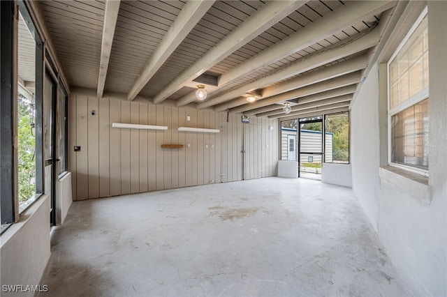 spare room featuring beamed ceiling and unfinished concrete floors