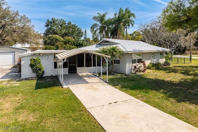 single story home featuring concrete driveway, metal roof, an attached carport, a front lawn, and stucco siding