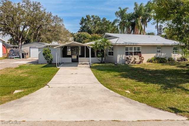 single story home with driveway, metal roof, a front lawn, and stucco siding