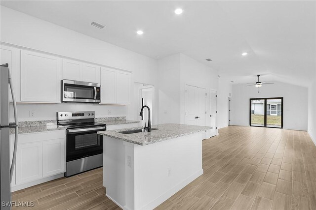 816 Gen D Macarthur Ave, Labelle, FL 33935 - kitchen featuring appliances with stainless steel finishes, a sink, light wood-style flooring, vaulted ceiling, and white cabinets