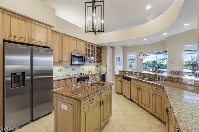 kitchen featuring decorative light fixtures, stainless steel appliances, light stone counters, and sink