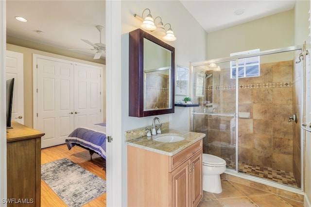 bathroom with toilet, a shower with door, ceiling fan, and vanity