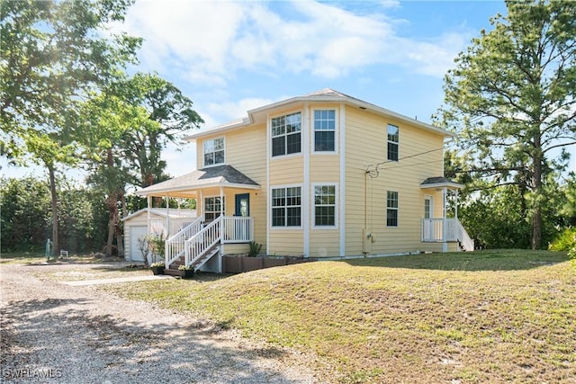 view of front facade featuring a front lawn, covered porch, an outdoor structure, a garage, and driveway