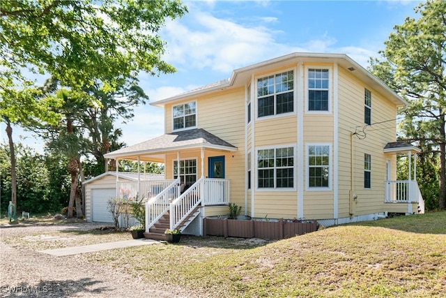 view of front of house featuring a porch, an outbuilding, a garage, and a front lawn