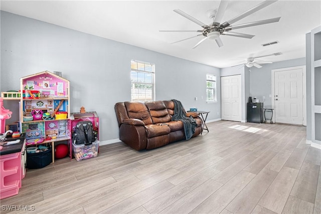 living area with visible vents, wood finished floors, baseboards, and ceiling fan