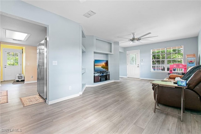 living area with plenty of natural light, ceiling fan, baseboards, and light wood-style floors