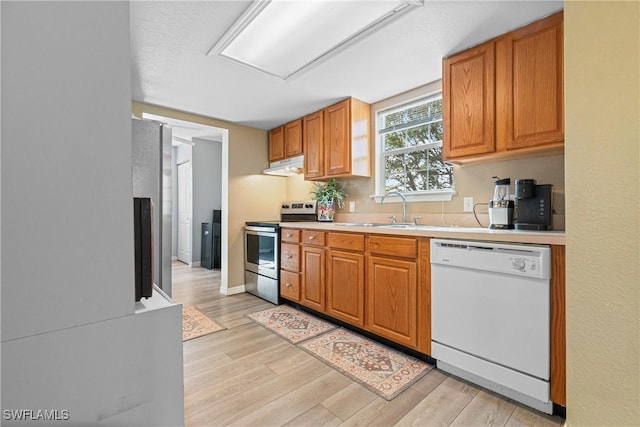 kitchen with stainless steel electric stove, white dishwasher, a sink, light countertops, and under cabinet range hood