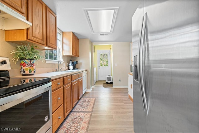 kitchen with under cabinet range hood, stainless steel appliances, plenty of natural light, and a sink