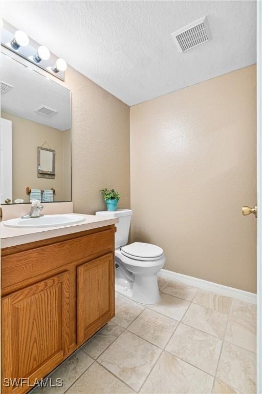 bathroom featuring visible vents, a textured ceiling, toilet, and vanity