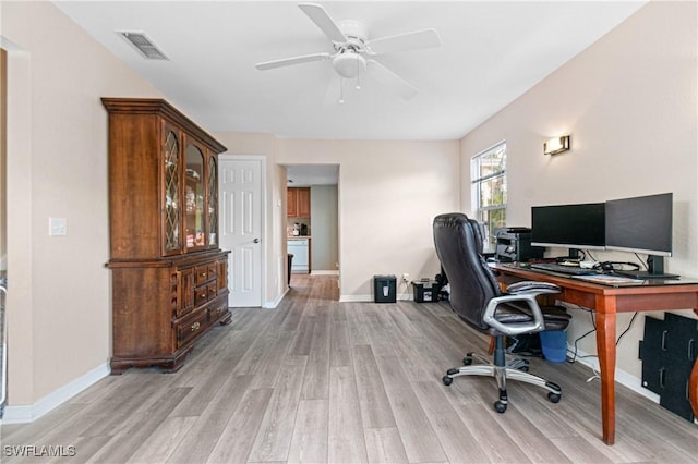 home office with visible vents, ceiling fan, baseboards, and light wood-style floors