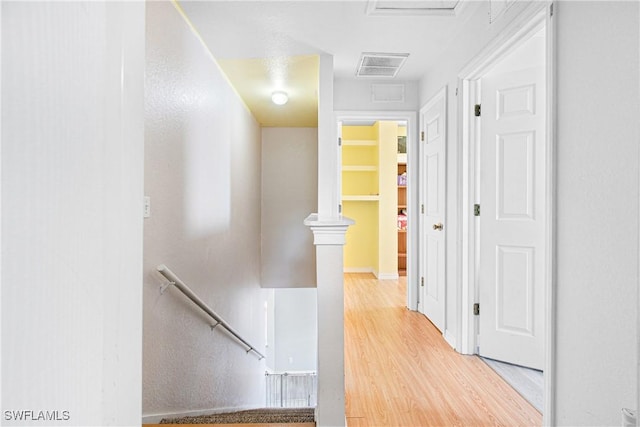 hallway with visible vents, an upstairs landing, and wood finished floors