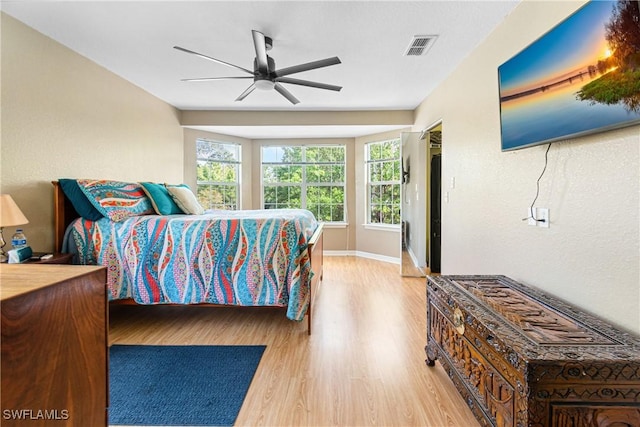 bedroom featuring ceiling fan, visible vents, baseboards, and wood finished floors