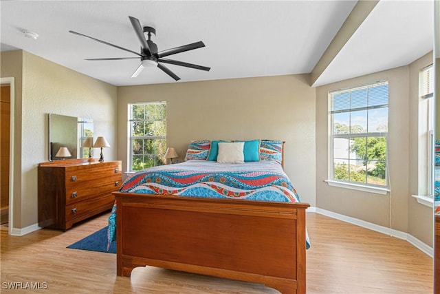 bedroom with light wood finished floors, a ceiling fan, and baseboards