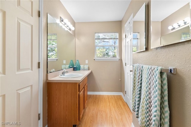 bathroom with a wealth of natural light, baseboards, wood finished floors, and vanity