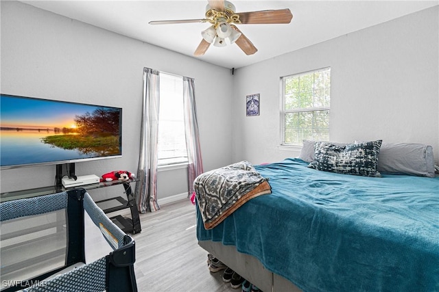 bedroom with light wood finished floors, baseboards, and a ceiling fan