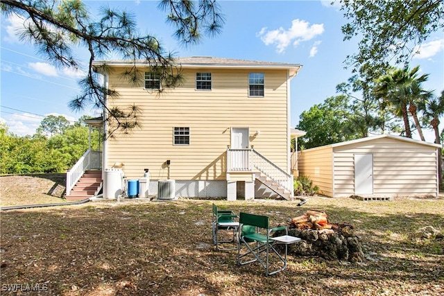 rear view of property featuring stairway, a storage shed, and an outdoor structure