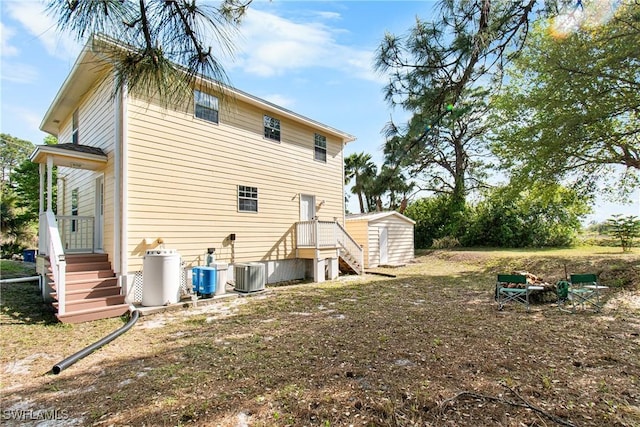 rear view of property featuring a storage shed, an outdoor structure, and cooling unit