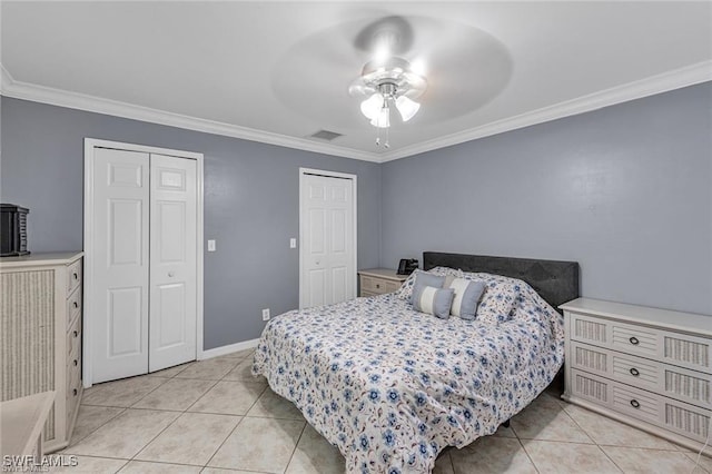 bedroom featuring crown molding, ceiling fan, multiple closets, and light tile patterned floors