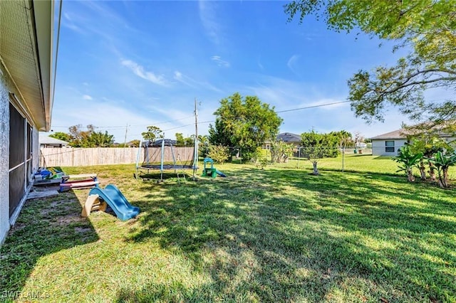 view of yard with a playground and a trampoline