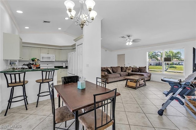 tiled dining space with lofted ceiling, ornamental molding, and ceiling fan with notable chandelier