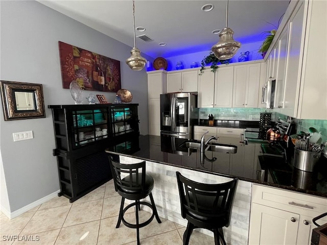 kitchen featuring decorative light fixtures, appliances with stainless steel finishes, white cabinetry, a sink, and light tile patterned flooring