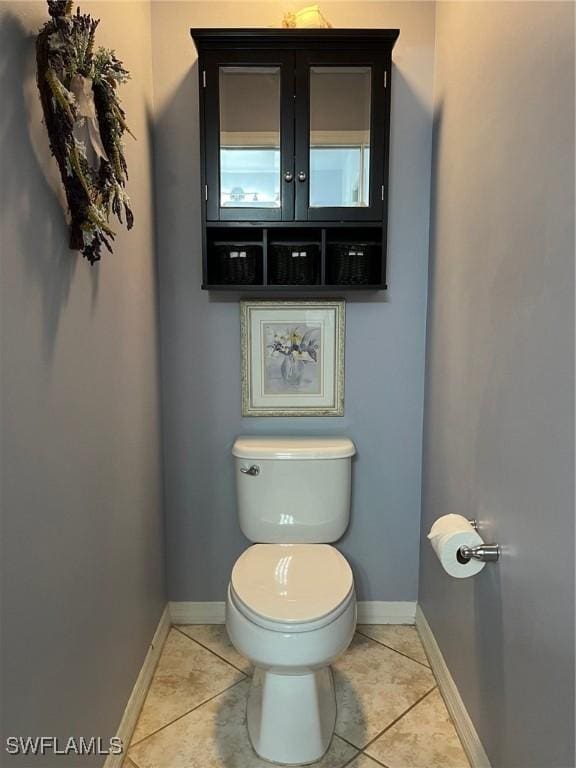 half bathroom with baseboards, toilet, and tile patterned floors