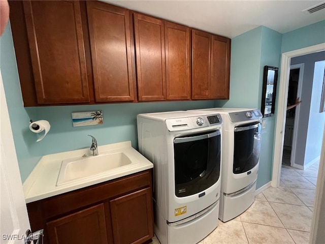 washroom featuring light tile patterned flooring, a sink, visible vents, independent washer and dryer, and cabinet space