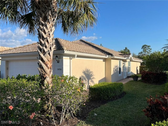 view of side of property with a garage, a yard, and stucco siding