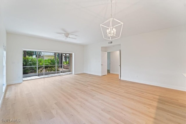 empty room featuring ceiling fan with notable chandelier and light hardwood / wood-style flooring