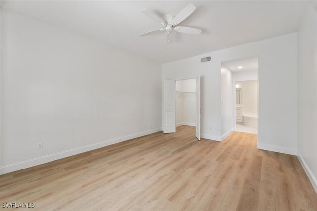 unfurnished bedroom featuring ensuite bath, light hardwood / wood-style flooring, ceiling fan, a spacious closet, and a closet