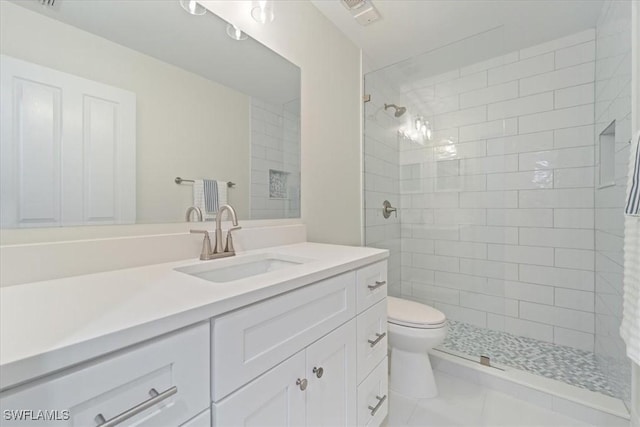 bathroom featuring vanity, toilet, and a tile shower