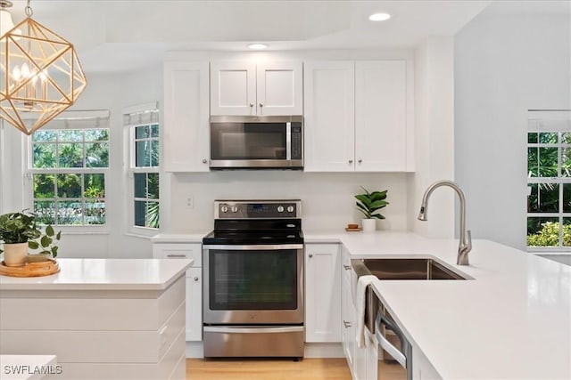 kitchen with white cabinetry, stainless steel appliances, and hanging light fixtures