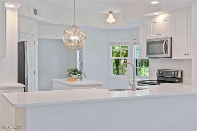 kitchen featuring sink, white cabinetry, decorative light fixtures, kitchen peninsula, and stainless steel appliances