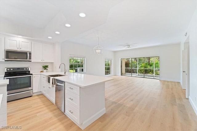 kitchen featuring sink, white cabinetry, hanging light fixtures, stainless steel appliances, and kitchen peninsula