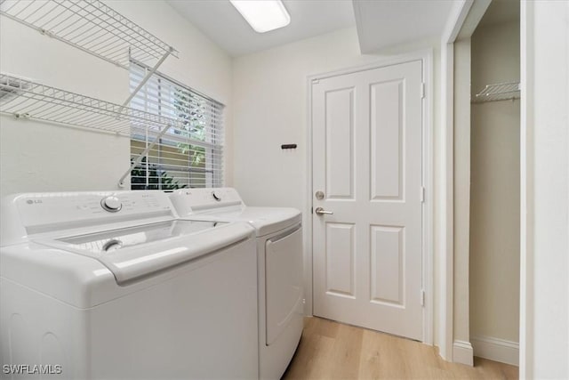 laundry area with light hardwood / wood-style flooring and washing machine and dryer